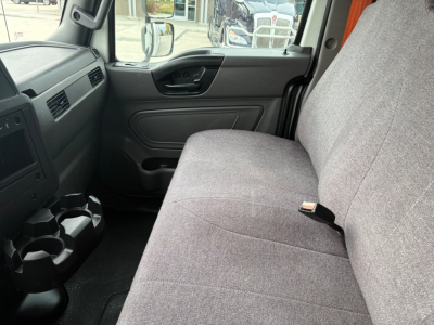 Truck interior front cabin with gray fabric bench seat, steering wheel, door panel, and center cup holders visible.