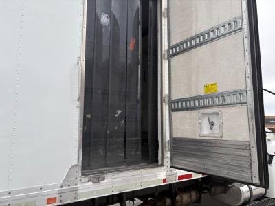 Truck refrigerated trailer rear doors open showing interior cargo area with vertical separators and metal tracks.
