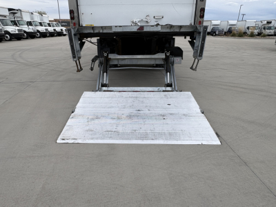 Rear view of a 2020 International MV607 refrigerated truck showing a lowered aluminum folding ramp extending from the rear cargo area.