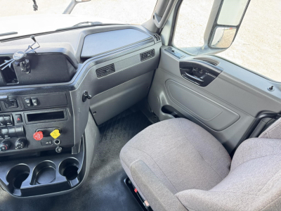 Truck cab interior showing steering wheel, dashboard, center console with cup holders and controls, passenger seat, and door panel.