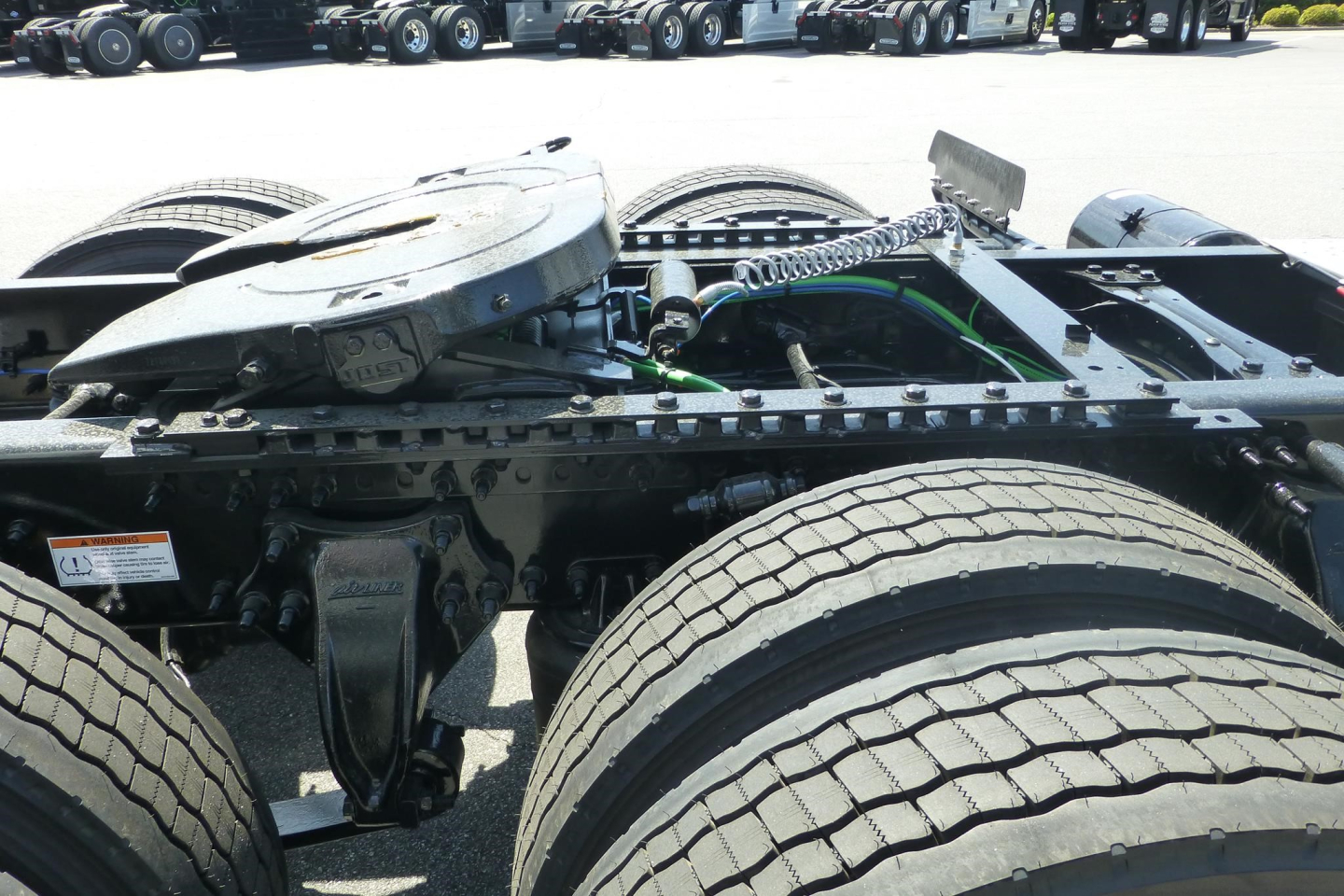Freightliner Cascadia chassis and drivetrain showing rear cab area with fifth wheel removed and dual rear axles, front tires visible, metal frame and hoses.