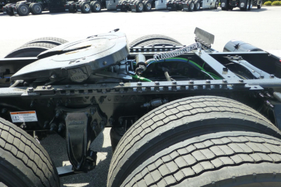 Freightliner Cascadia chassis and drivetrain showing rear cab area with fifth wheel removed and dual rear axles, front tires visible, metal frame and hoses.