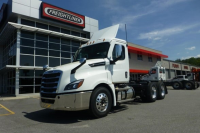 Truck cab and chassis in a Freightliner dealership lot showing a white 2027 Freightliner Cascadia 126 day cab with front view and other trucks in the background.