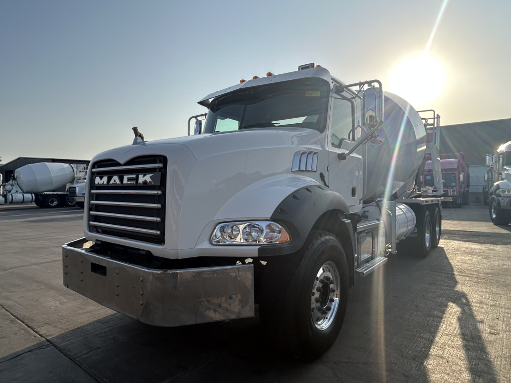 Mack GR64B mixer truck in used condition with white cab and chrome bumper, front view showing grille and headlights.