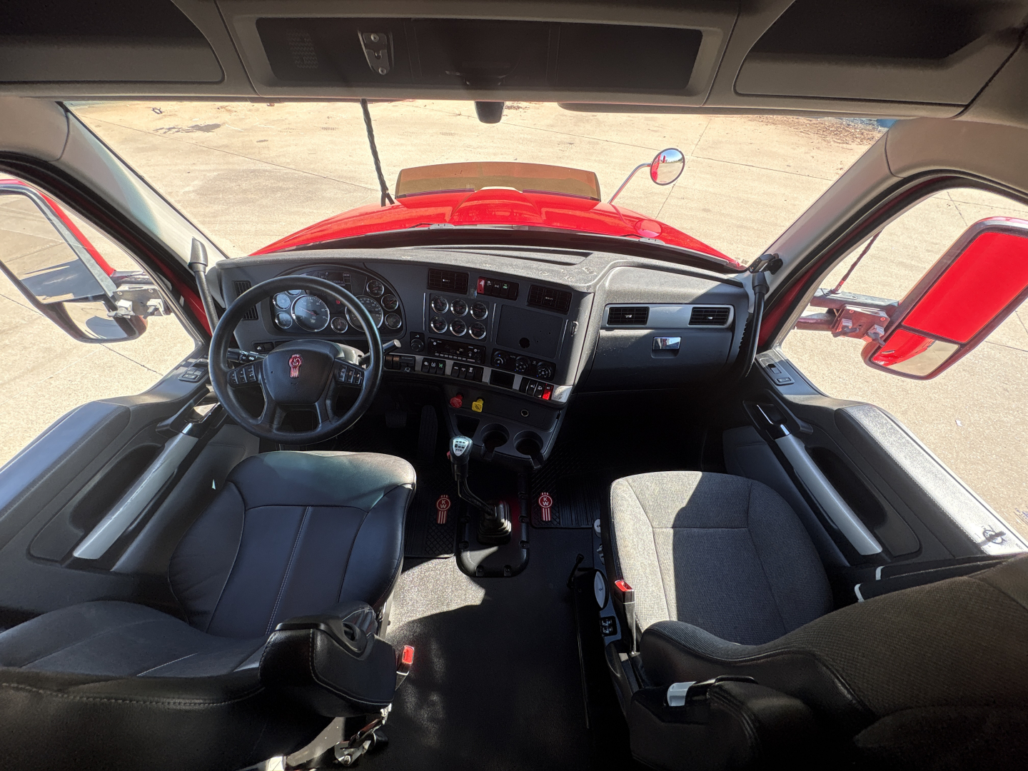 Kenworth T680 truck cab interior showing steering wheel, dashboard, two seats, and central control panel.