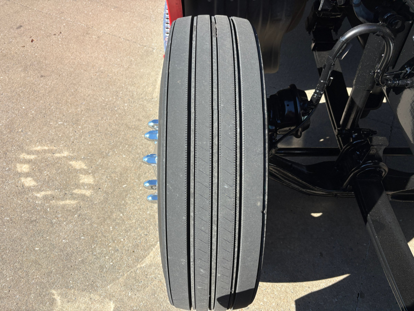 Kenworth T680 front dual axle wheel area showing a single tire with four visible lug nuts and suspension components.