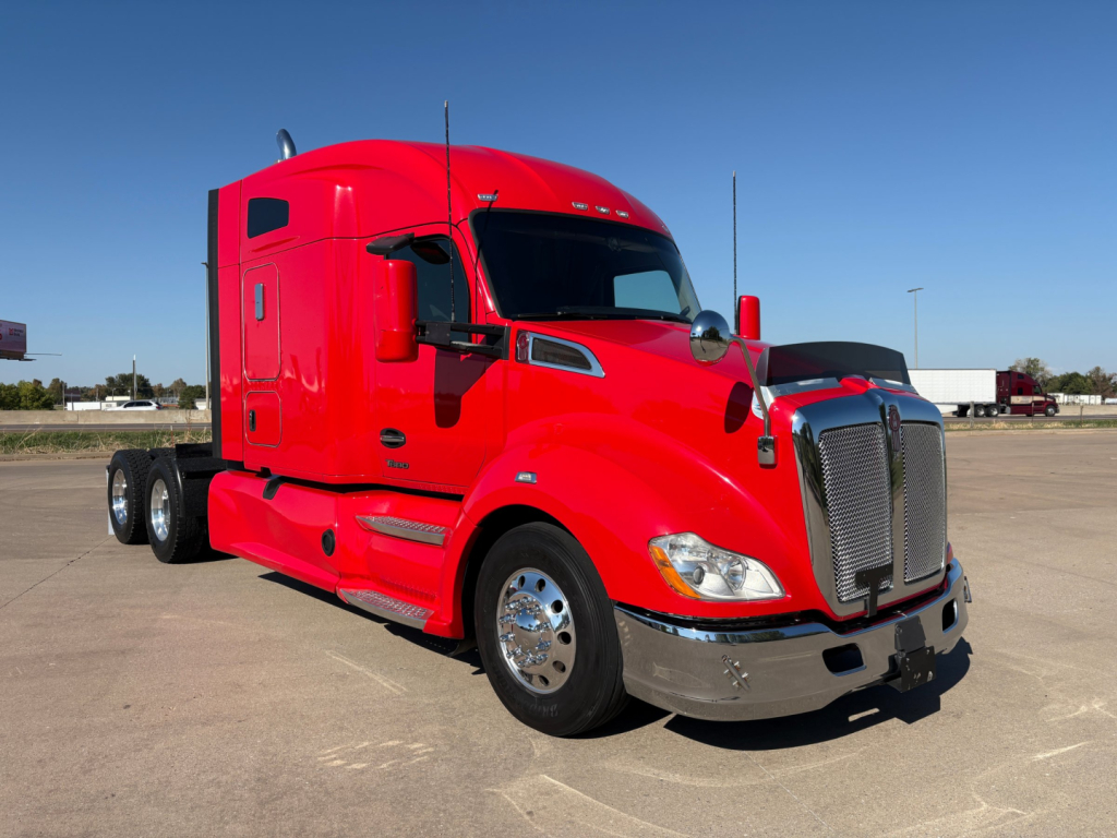 Kenworth T680 red sleeper tractor truck in a parking lot, side view emphasizing front grille and chrome bumper.