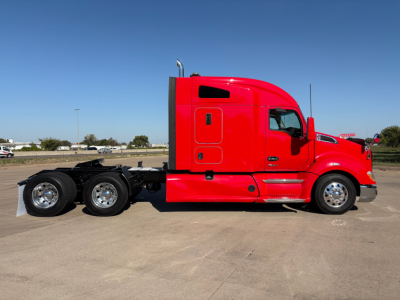 Kenworth T680 2022 red conventional sleeper truck side view showing cab and rear wheels in a parking lot.