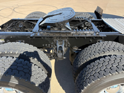 Kenworth T680 chassis area showing fifth wheel, dual rear axles, and fuel/air lines with visible hitch assembly.