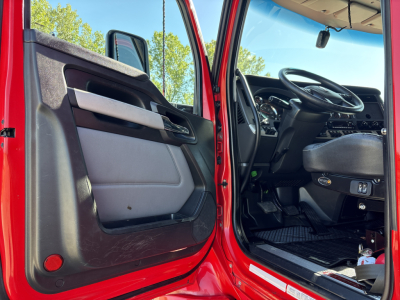 Kenworth T680 truck cab interior visible through open driver door, showing steering wheel, dashboard, and door panel.