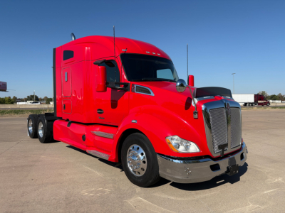 Kenworth T680 red sleeper tractor truck in a parking lot, side view emphasizing front grille and chrome bumper.