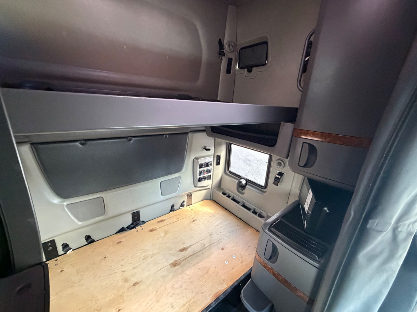 Interior sleeper cab area of a used 2021 International LT625 showing wooden floor bed area and side paneling with storage compartments.
