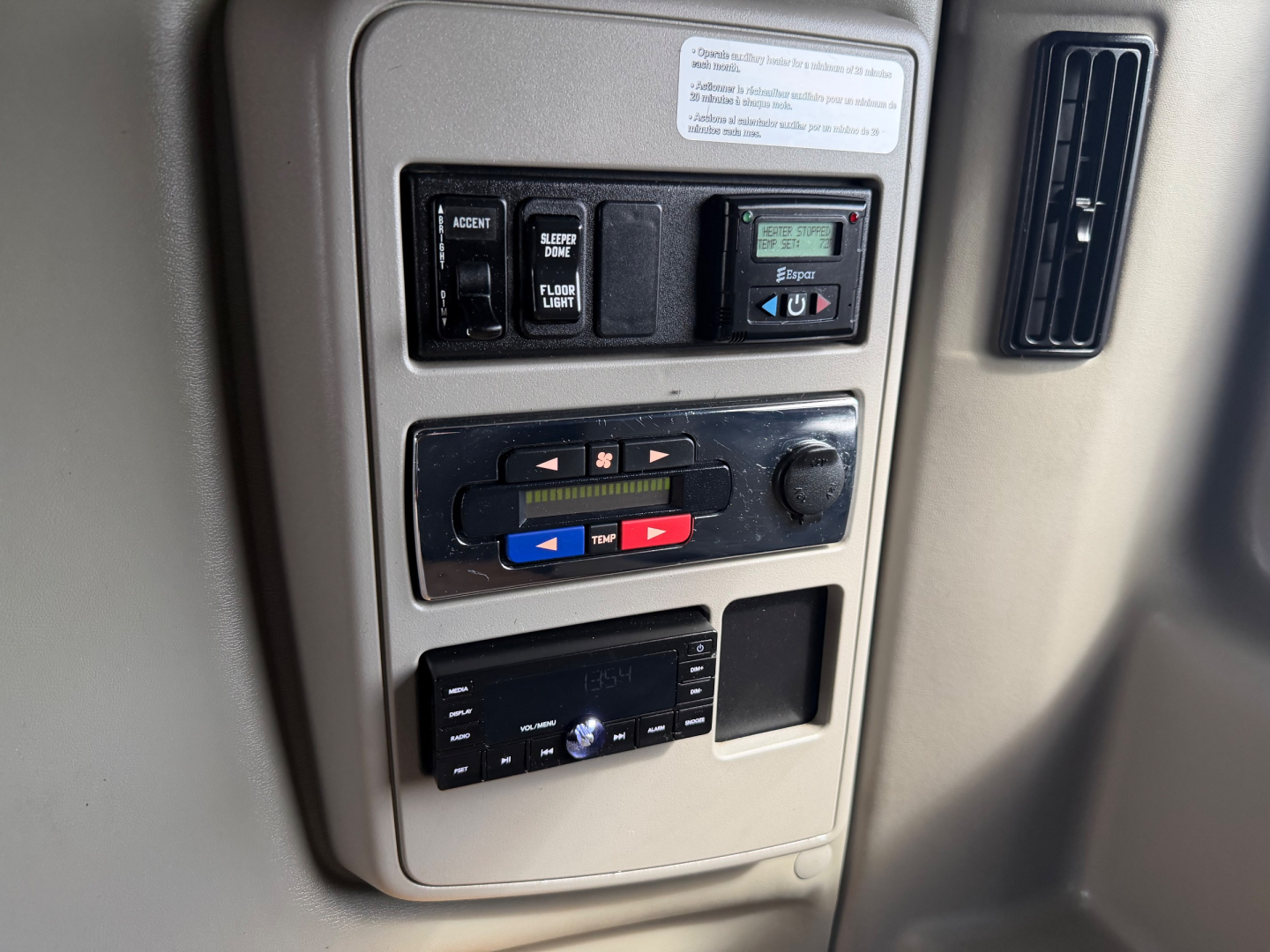 Controls panel in truck cab showing climate switches, audio head unit, and auxiliary controls with labeled buttons.