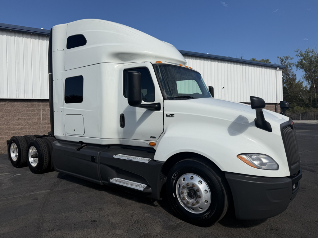 Truck cab in profile showing International LT625 sleeper with dual rear axles and front fenders.