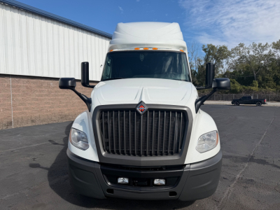 Truck front view of a white 2021 International LT625 sleeper cab showing large black grille, dual side mirrors, and roof air deflector.
