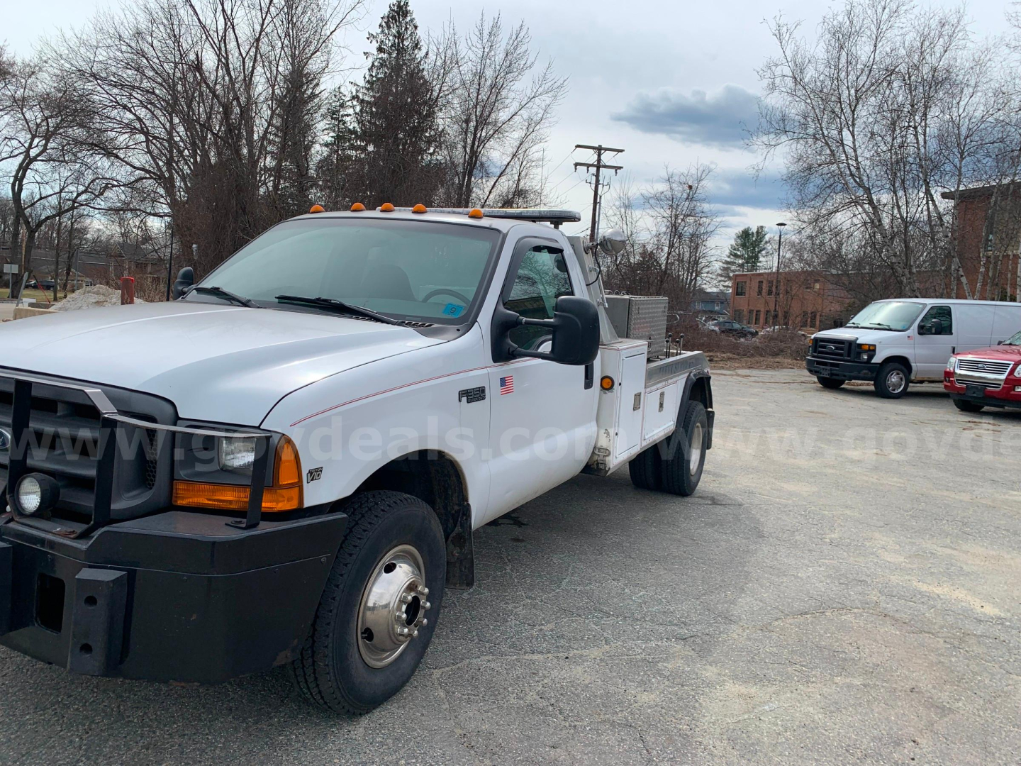 Ford F-350 tow truck cab and flatbed in a parking lot showing front grille, amber clearance lights, and side mirrors.