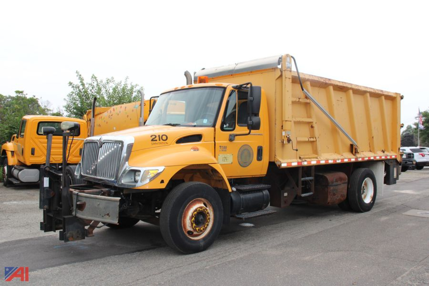 International WorkStar 7300 dump truck showing large orange body with dump bed and front grille; 210 badge on the door; equipment in-service.