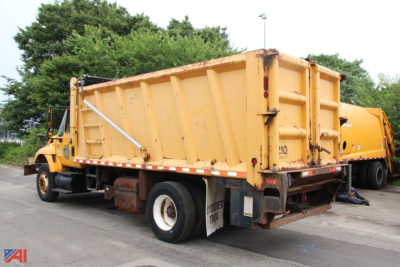 Dump truck in-service showing large yellow dump bed of an International WorkStar 7300 with rear tailgate and dual rear wheels.