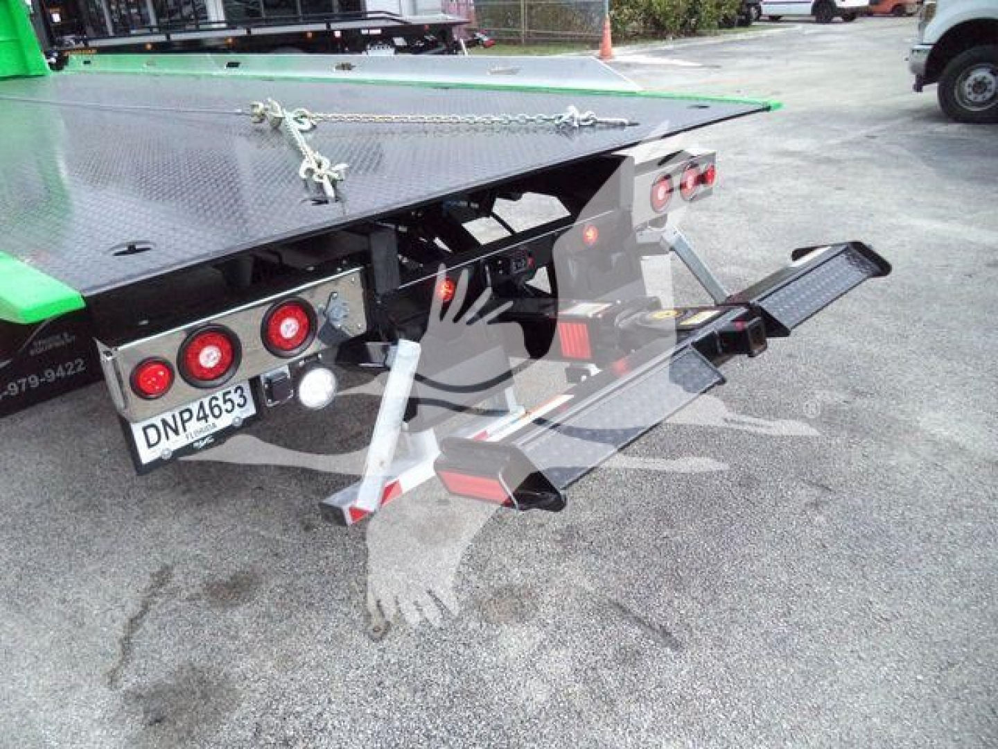 Truck rear showing rollback equipment on a 2026 Peterbilt 536 with diamond-plate platform, taillights, hydraulic lift, and ramp extended.