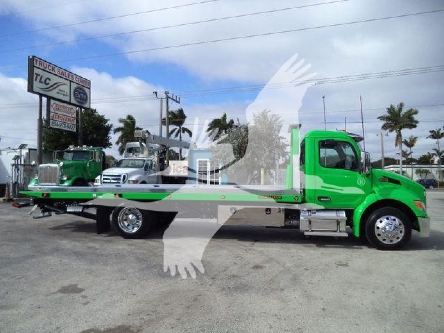 Green Peterbilt 536 rollback tow truck viewed from side showing flatbed and cab with chrome mirrors.