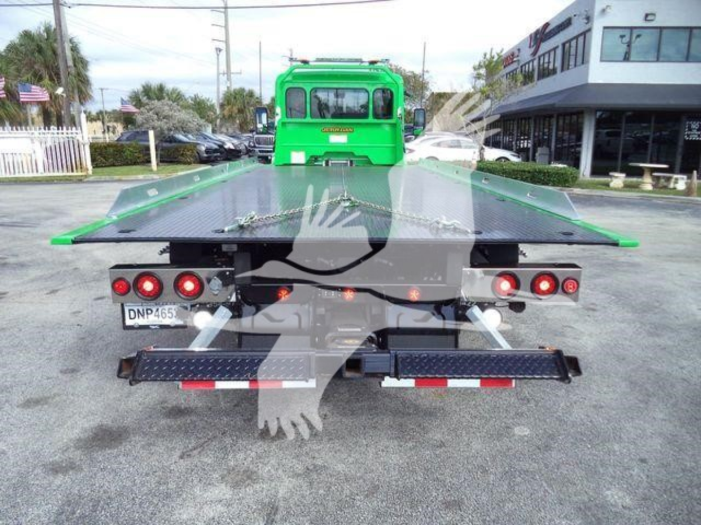 Back view of a green Peterbilt 536 rollback truck with a flatbed tow bed and work lights.