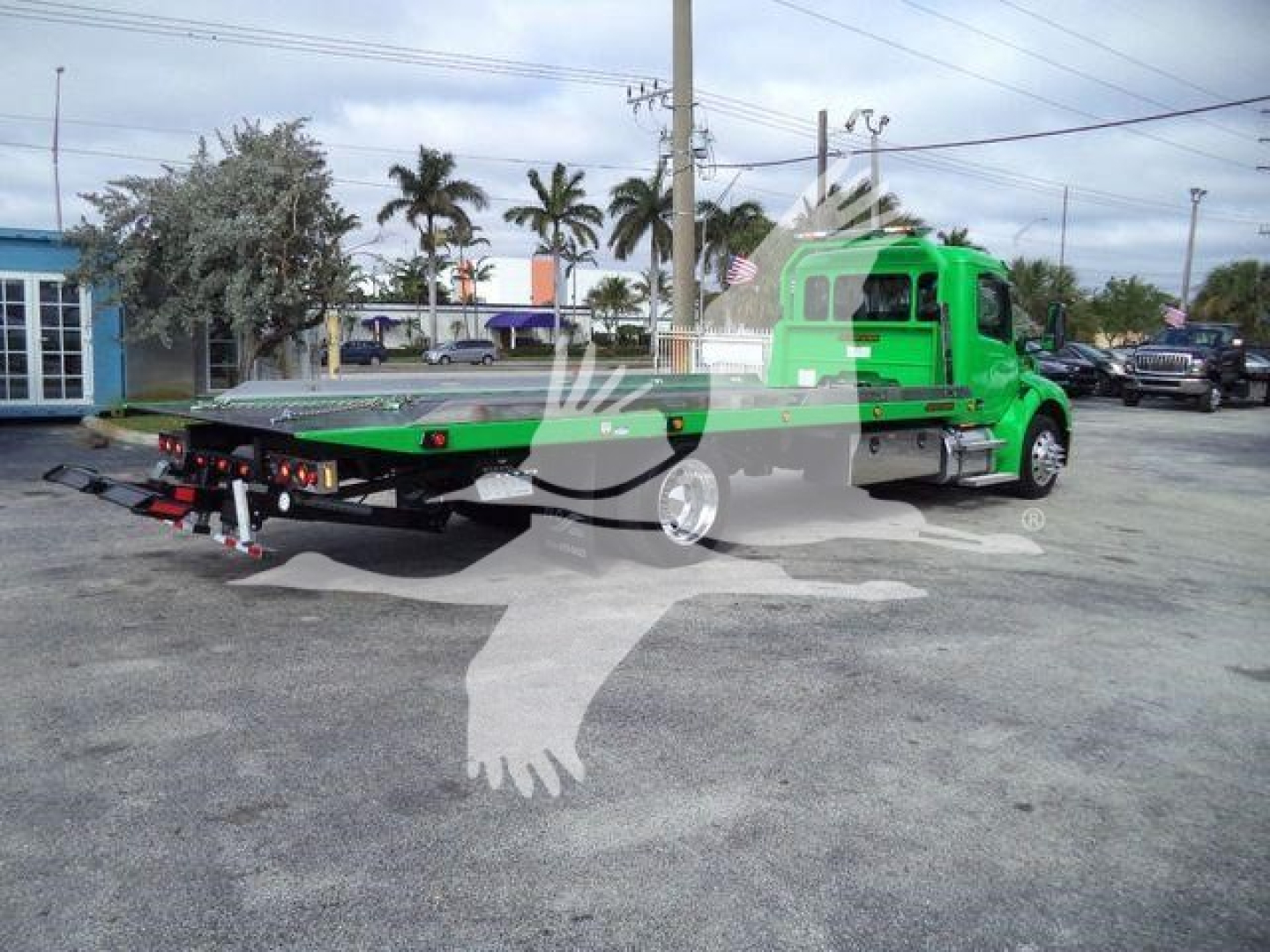 Green Peterbilt 536 rollback tow truck with flatbed rear view showing chassis and taillights.