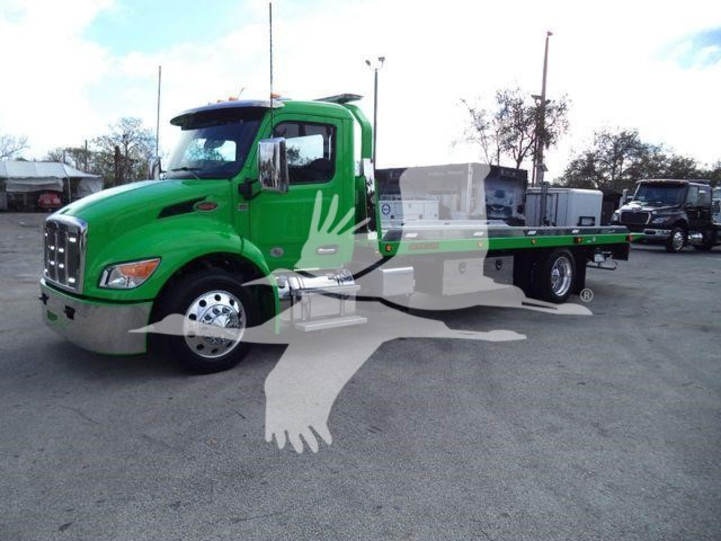 Green Peterbilt 536 rollback truck seen from side/front angle with flatbed and chrome bumper