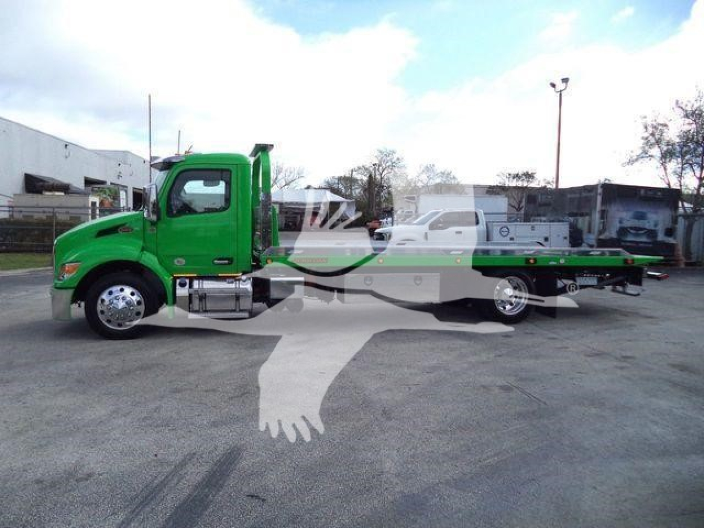 Green Peterbilt 536 rollback tow truck side view showing flatbed with wheel lift and chrome fuel tanks.