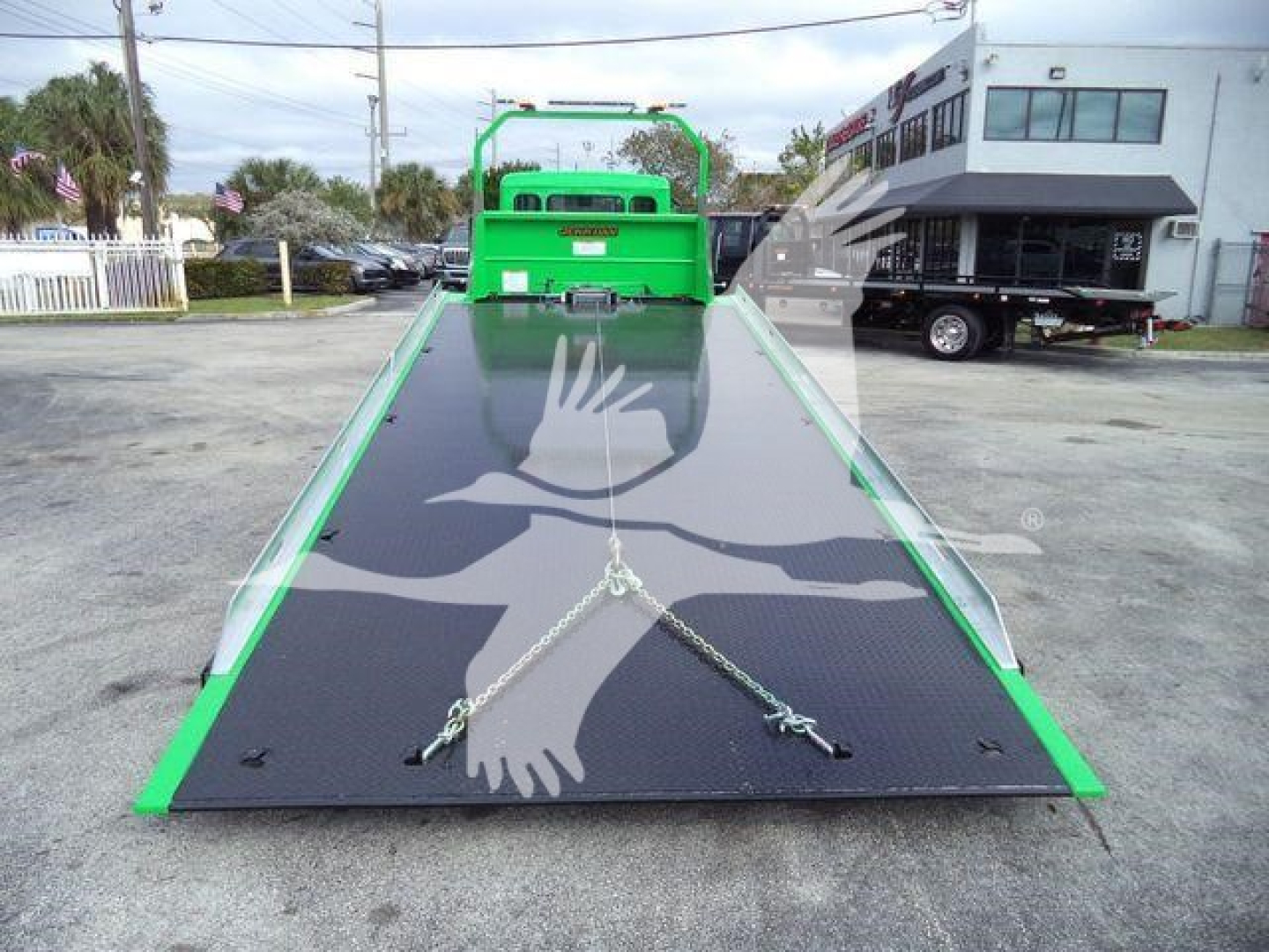 Green Peterbilt rollback truck bed with black anti-slip surface and chains, viewed from the rear looking forward