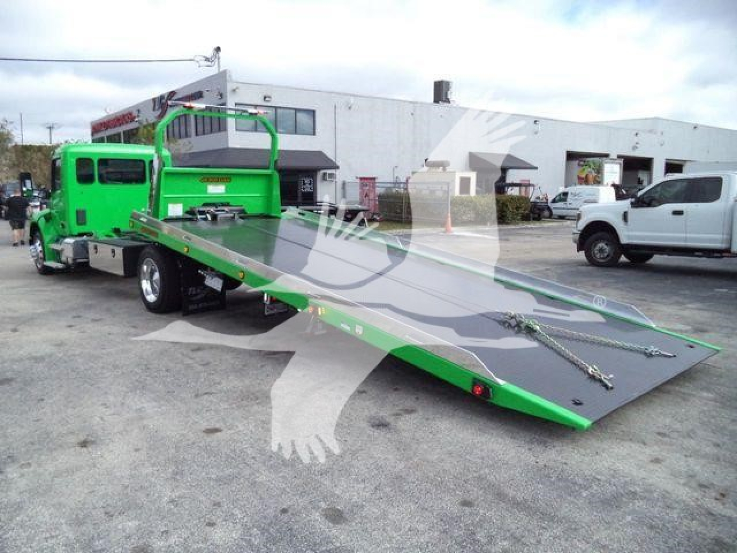 Peterbilt 536 rollback tow truck with a bright green cab and a long flatbed ramp
