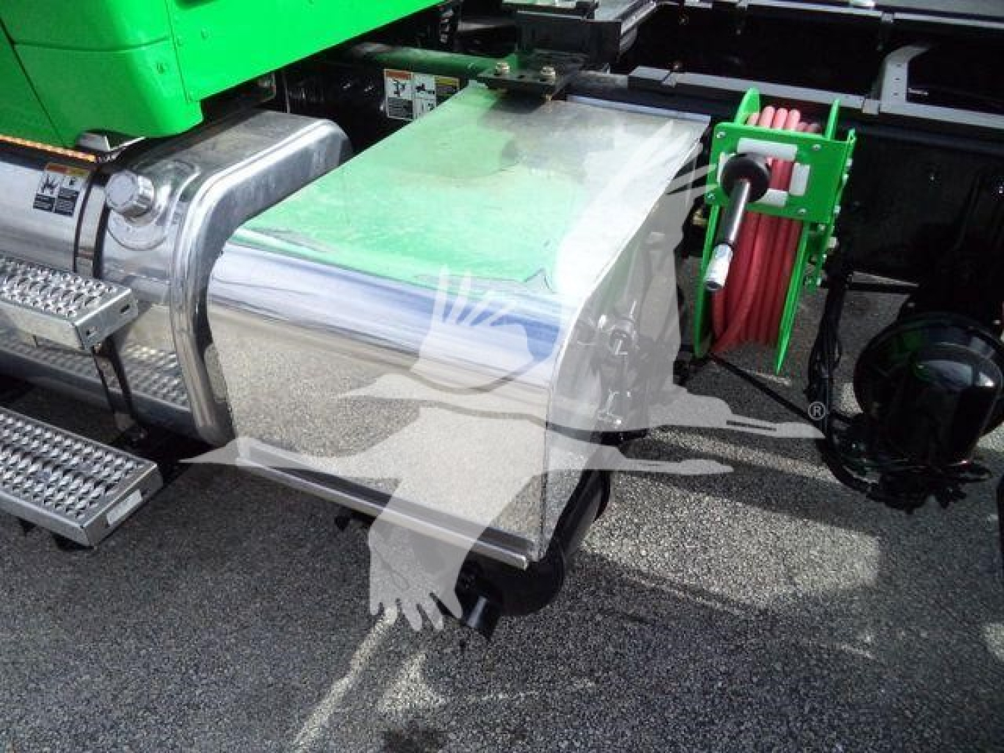 Peterbilt 536 rollback truck side view showing chrome fuel tank and green reel hose, with metal steps and access panels.