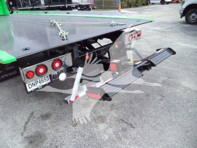 Truck rear showing rollback equipment on a 2026 Peterbilt 536 with diamond-plate platform, taillights, hydraulic lift, and ramp extended.