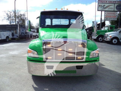 Green 2026 Peterbilt 536 rollback truck front view with chrome grille and bumper, stock number 2PETE536XLP22 visible in the background.