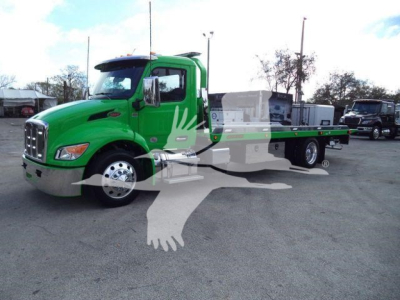 Green Peterbilt 536 rollback truck seen from side/front angle with flatbed and chrome bumper