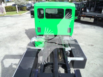 Green Peterbilt truck cab section with rollback chassis and fifth wheel attachment, rear view showing hitch and wiring, stock number visible.