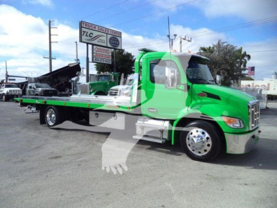 Peterbilt 536 rollback tow truck in bright green with flatbed and hydraulic winch, side mirrors, chrome bumper, and front grille visible.