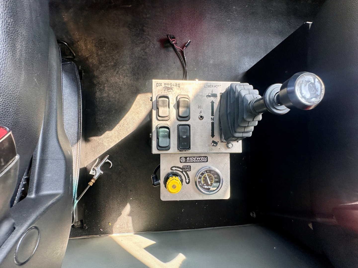 Kenworth T880 dash area showing control switches, ignition-like knob, and a pressure gauge with yellow knob and lever.