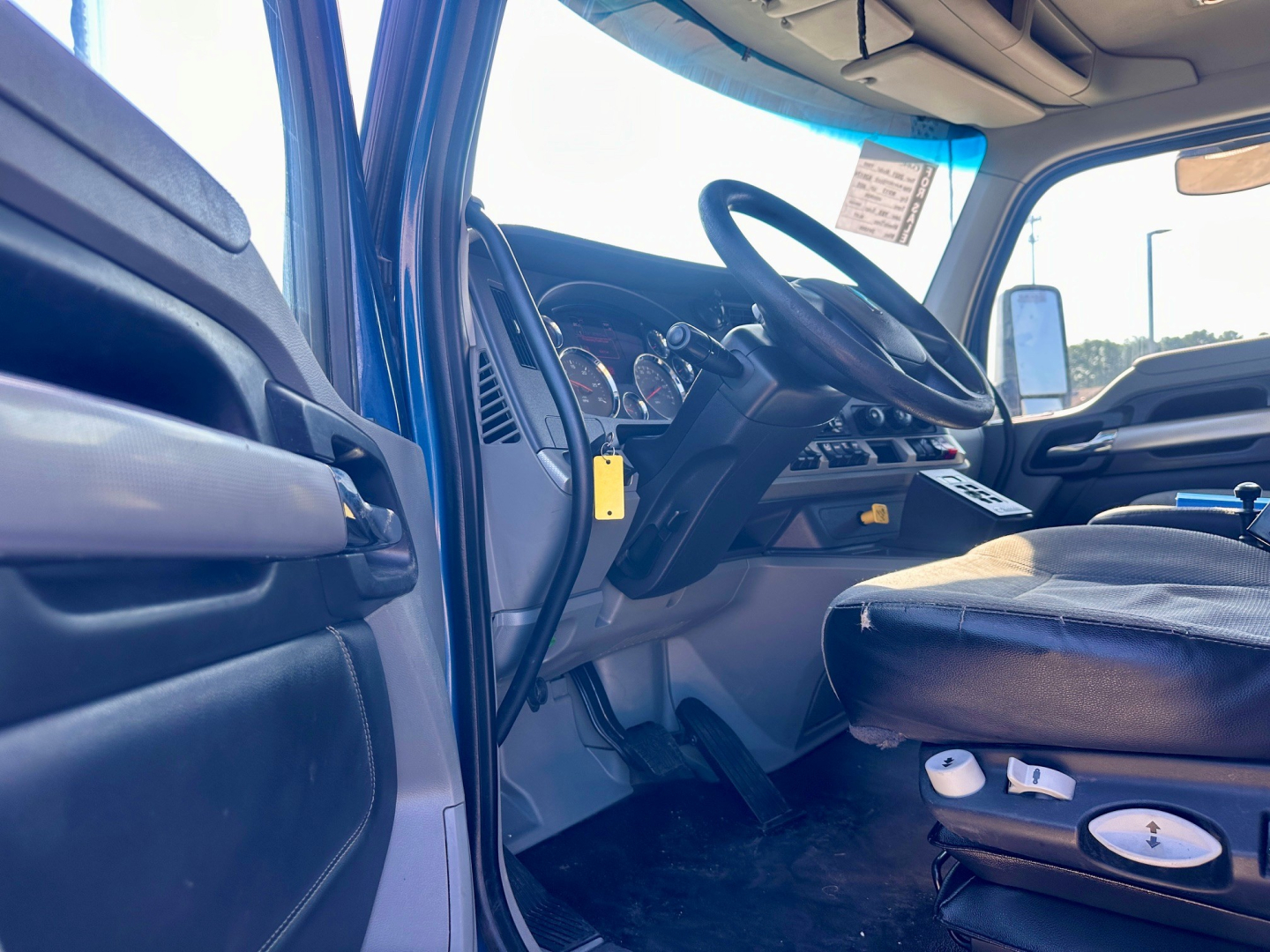 Interior of a 2021 Kenworth T880 truck cab showing steering wheel, dashboard gauges, and driver seat with controls.