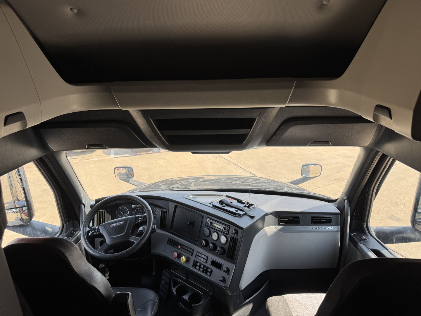Cab interior of a Freightliner truck with dashboard controls and steering wheel; no legible labels visible in this view.