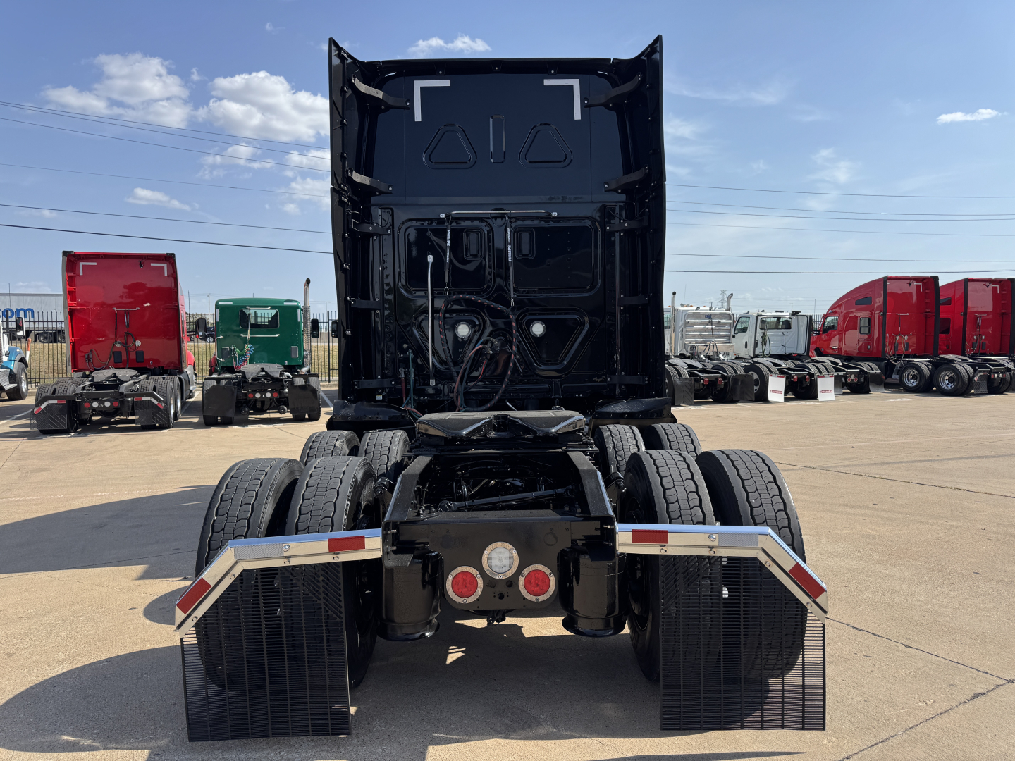 Freightliner chassis rear view showing fifth wheel area, dual rear axles, mud flaps, and bumper with lights.