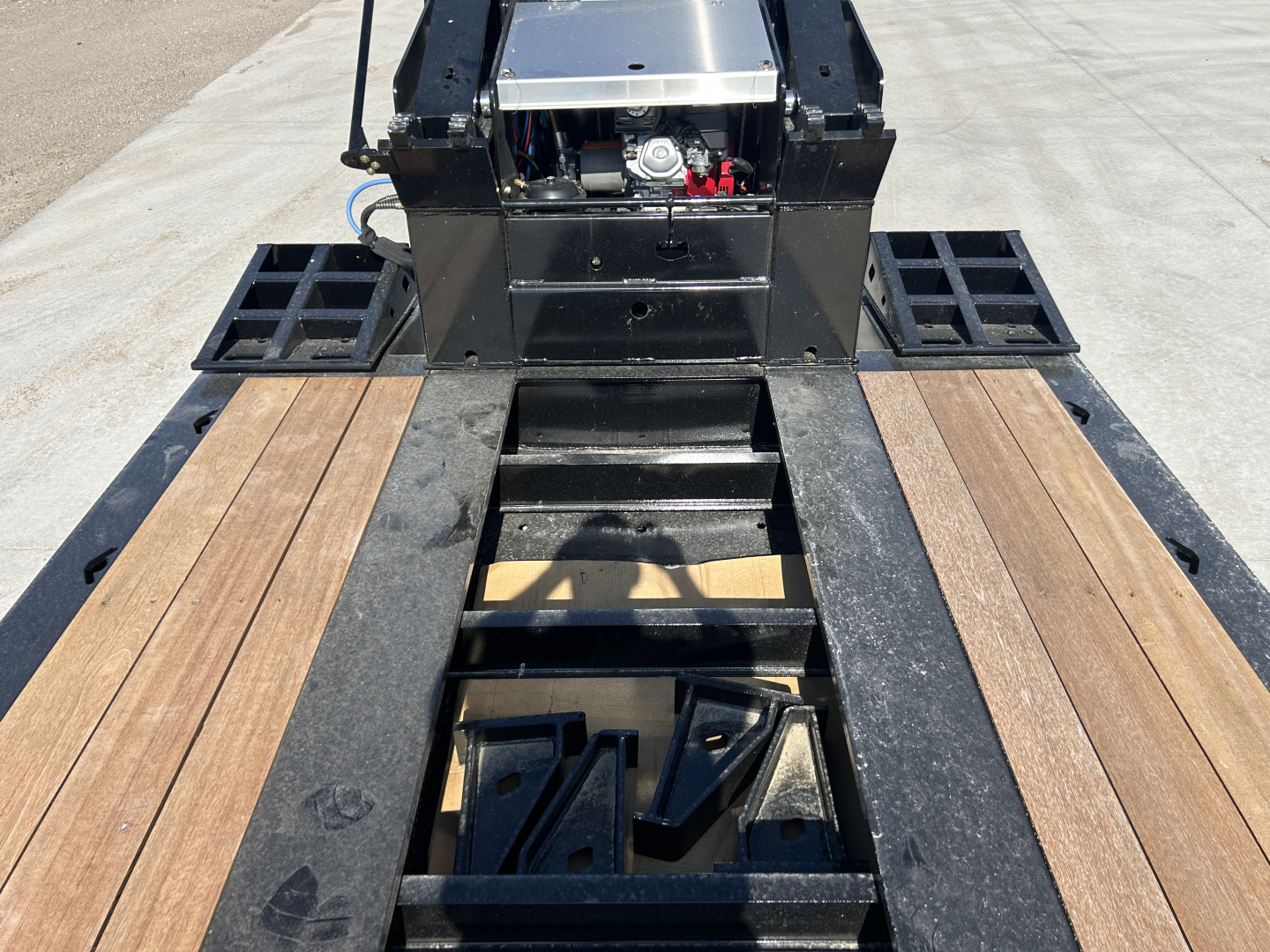 Trailer deck and gooseneck area of a 2027 Alpha A110HDG 18 LDH lowboy trailer showing wood decking, steel frame, and mechanism at the center.