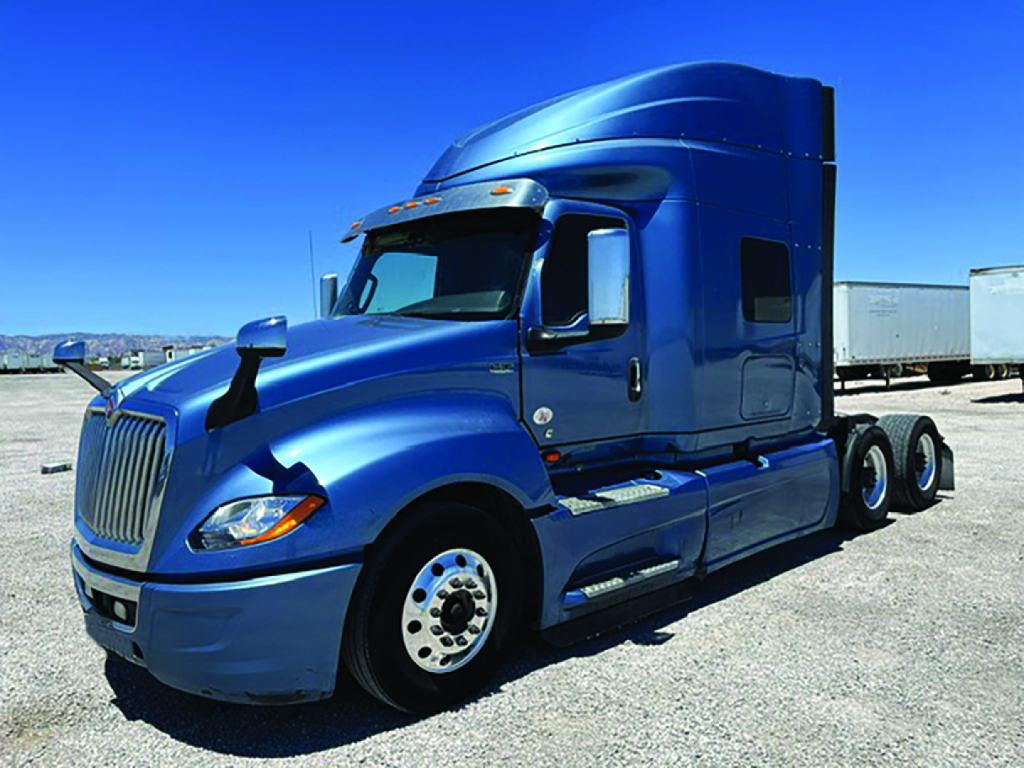 Blue International LT625 sleeper truck in profile view showing front grille, dual rear axles, and cab sleeper with side exhaust.
