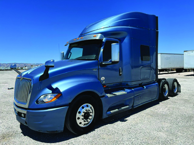 Blue International LT625 sleeper truck in profile view showing front grille, dual rear axles, and cab sleeper with side exhaust.