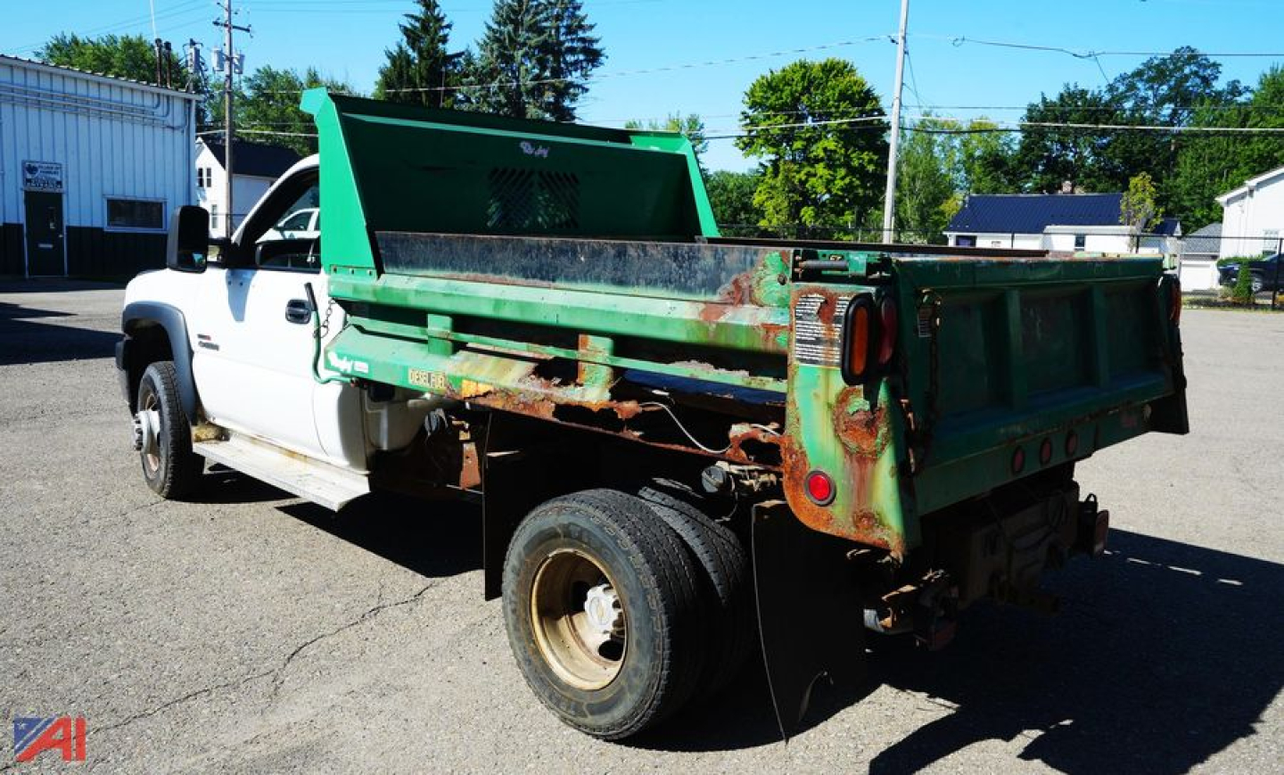 Dump truck bed and cab of a 2002 Chevrolet Silverado 3500 dump truck, white cab with green dump bed, rust visible on bed sides, rear wheels visible.