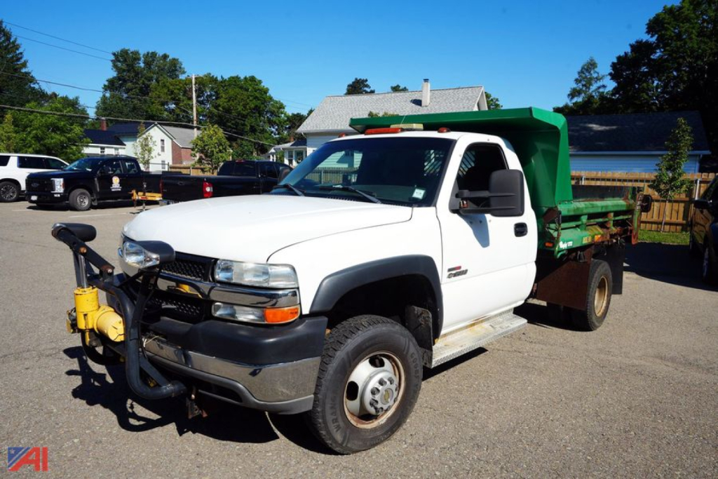 Chevrolet Silverado 3500 dump truck in a parking lot with green dump bed viewed from front-left side showing hitch and dual rear wheels.