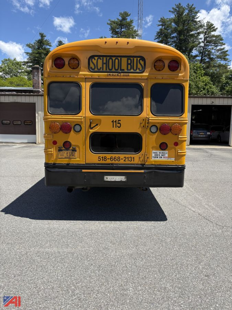 School bus rear view with yellow body and black bumper showing number 115 and contact info, ‘SCHOOL BUS’ sign, taillights.