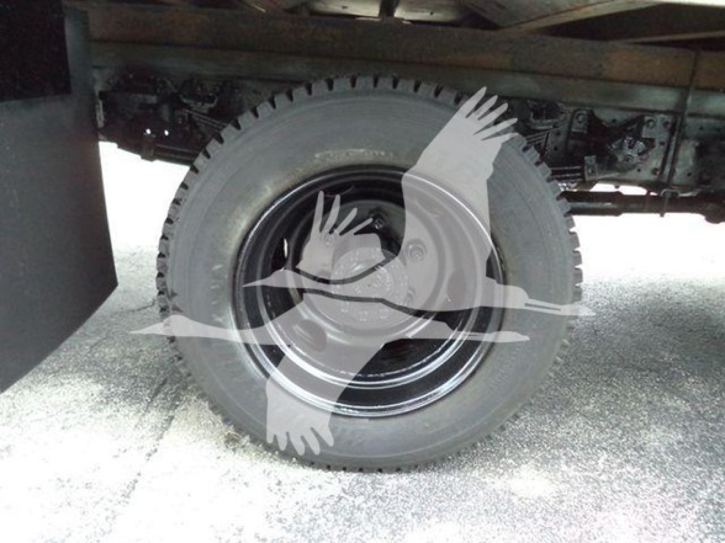 Wheel and undercarriage of a refrigerated 2020 Hino 195 truck showing a black rim and tire with chassis components.