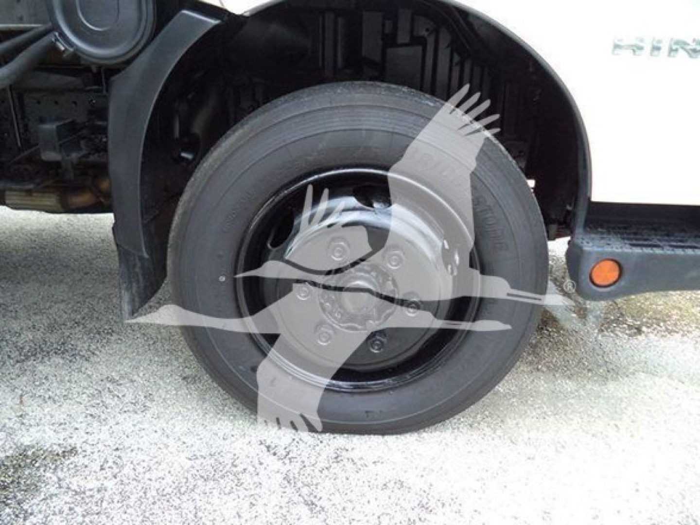 Front wheel and fender area of a 2020 Hino 195 refrigerated truck showing wheel well and tire.