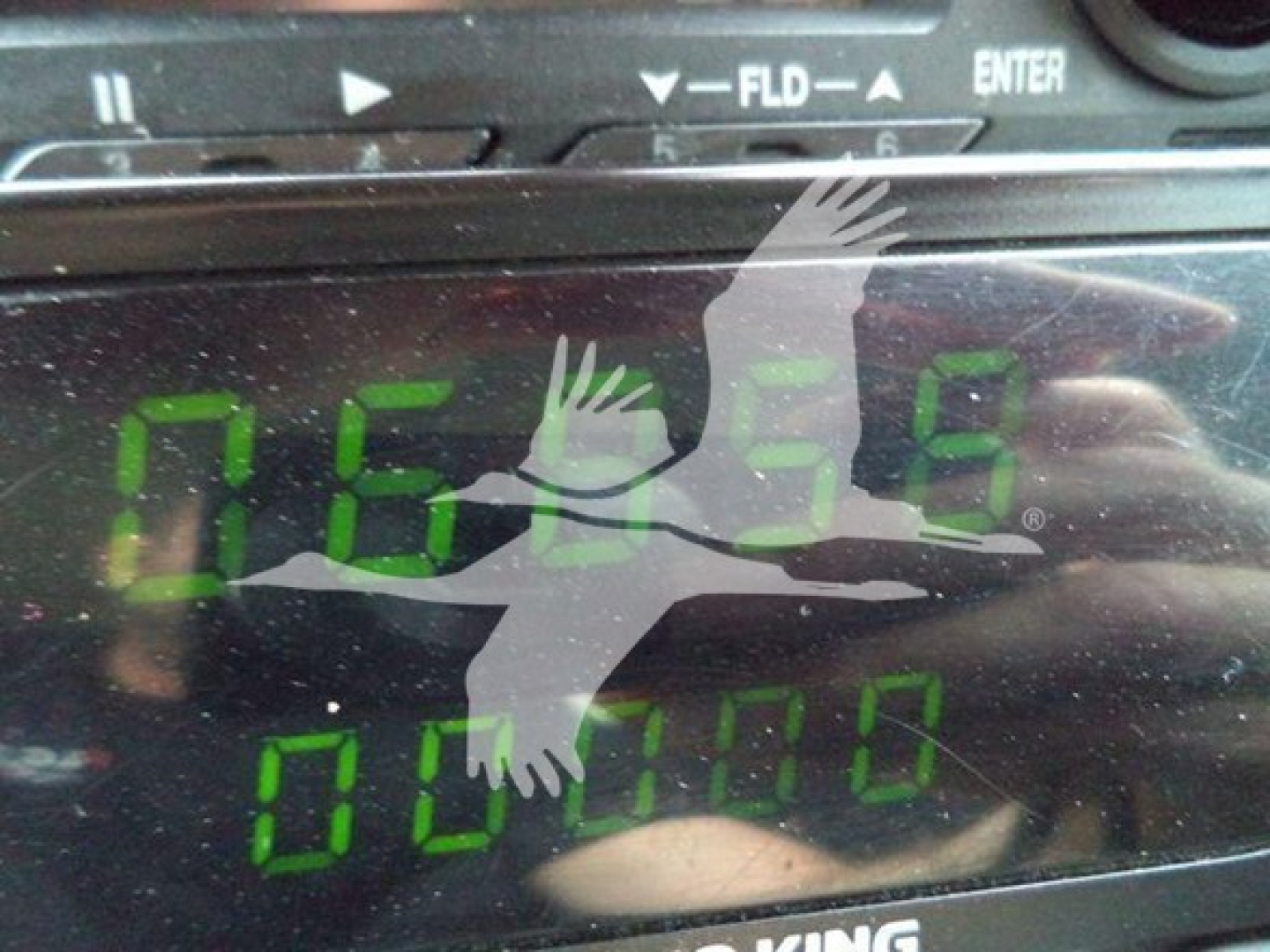Dashboard display showing digital readout with green numbers, including '0059' and '000000' partially obscured by reflection.