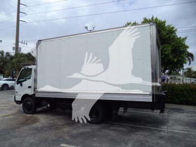 Truck side view showing a refrigerated box on a white cab with a large graphic of a flying bird on the side.